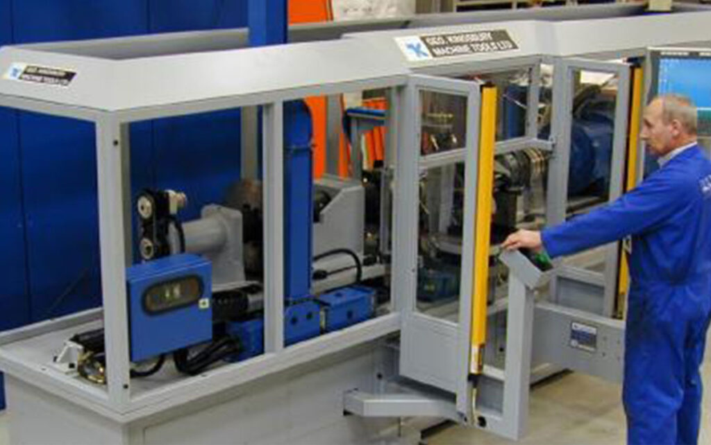 A man standing in front of a machine in a factory.