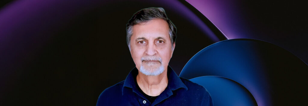 A man with a gray beard and short hair is wearing a dark polo shirt. The background features abstract dark and purple-blue shapes.