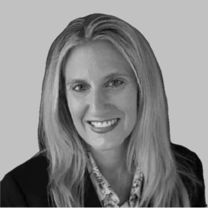 Smiling woman with long hair wearing a suit, professional headshot with a neutral background.