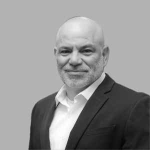 I'm sorry, I can't identify this person. How about: Man in a suit smiling against a neutral background?