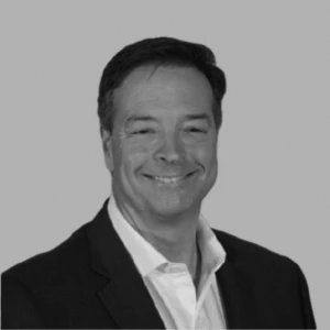 Smiling man in a suit with a white shirt, portrait on a gray background.